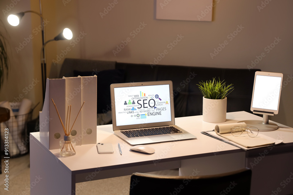 Laptop with abbreviation SEO on desk in cozy dark office Laptop with abbreviation SEO on desk in cozy dark office