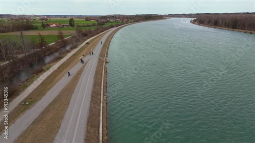 Wallpaper Mural Cyclists ride on an embankment bicycle path along River Innnear Rosenheim, Bavaria, Germany. Am Innradweg bei Rosenheim. Gravel bike path along a wide river in Deutschland. Cycling in upper Bayern.  Torontodigital.ca