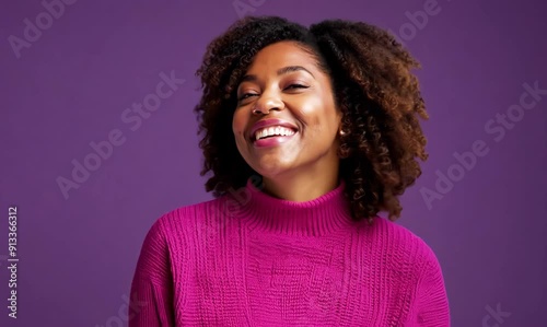smiling african american woman in pink sweater over purple background