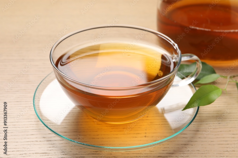 Refreshing green tea in cup and leaves on wooden table, closeup Refreshing green tea in cup and leaves on wooden table, closeup