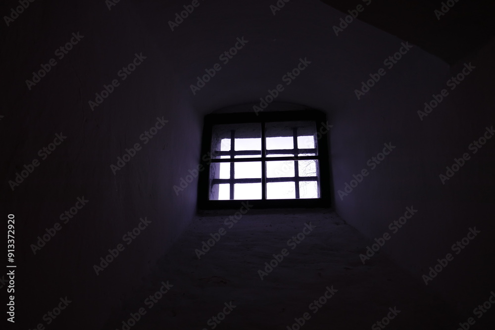 View from dark interior outside through small barred window View from dark interior outside through small barred window