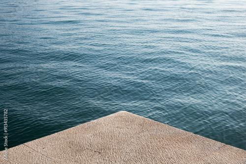 The blue adriatic sea washes up against the limestone Quayside in Split, Croatia