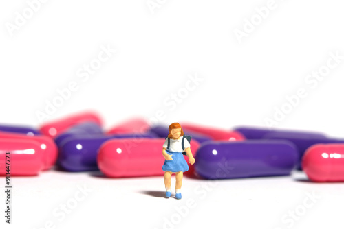 Miniature people toy figure photography. A girl student standing in front of medical drug pill. Isolated on white background photo