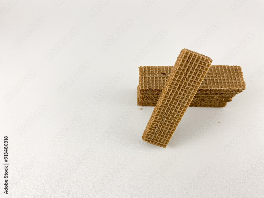 chocolate wafer biscuits arranged on a white background. One biscuit stands upright, leaning against a stack of biscuits.