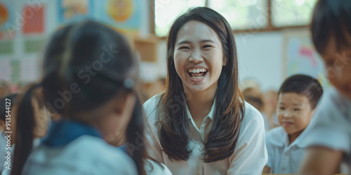 A female teacher smiles brightly as she interacts with her students in a classroom setting.. asian woman