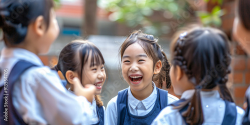 Four young schoolgirls in uniform laugh together outside of their school.