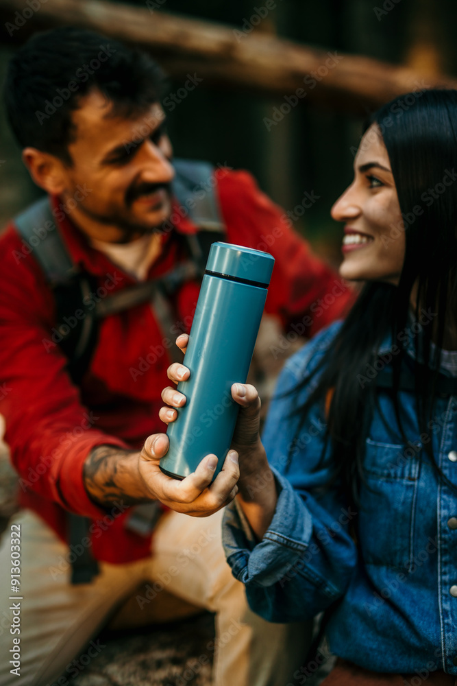 Hiker holding insulated drink container while sitting with boyfriend Hiker holding insulated drink container while sitting with boyfriend