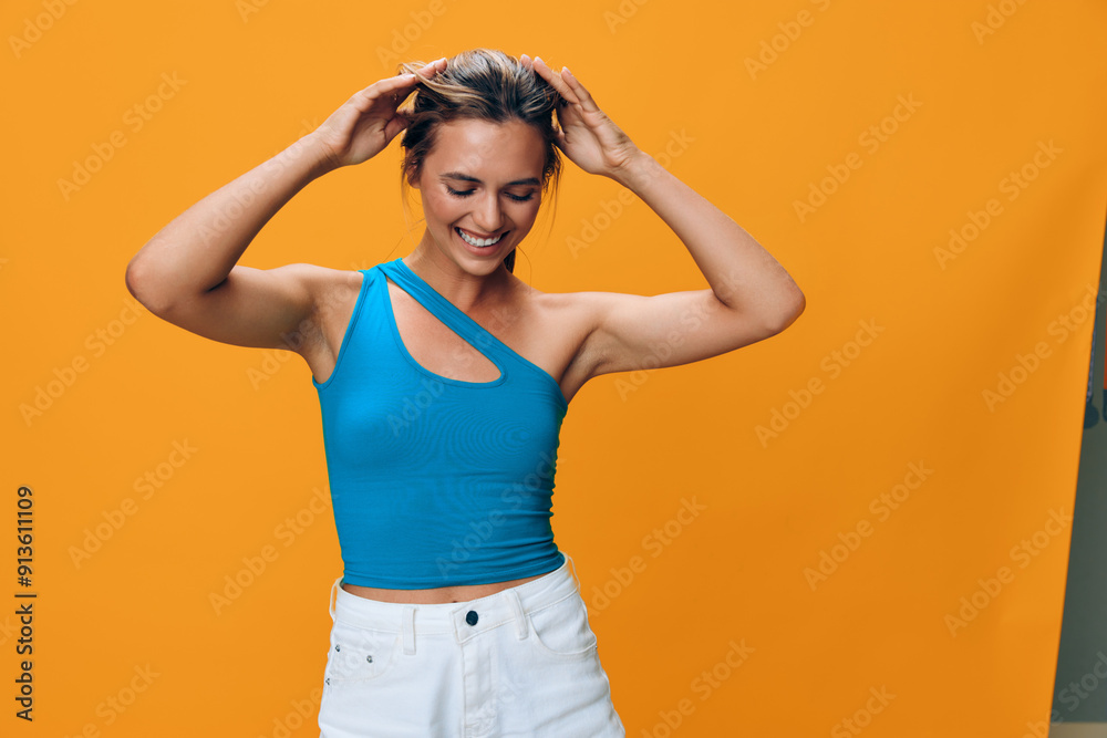 Pensive woman in chic summer outfit, white shorts and blue top poses with hands on head on vibrant orange background Pensive woman in chic summer outfit, white shorts and blue top poses with hands on head on vibrant orange background