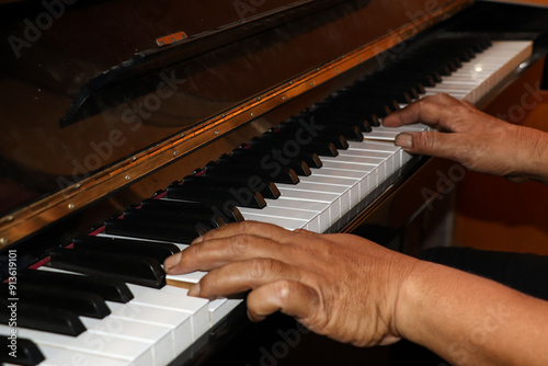 A piano is being played by a pianist, the pianist's hands are seen playing the piano keys