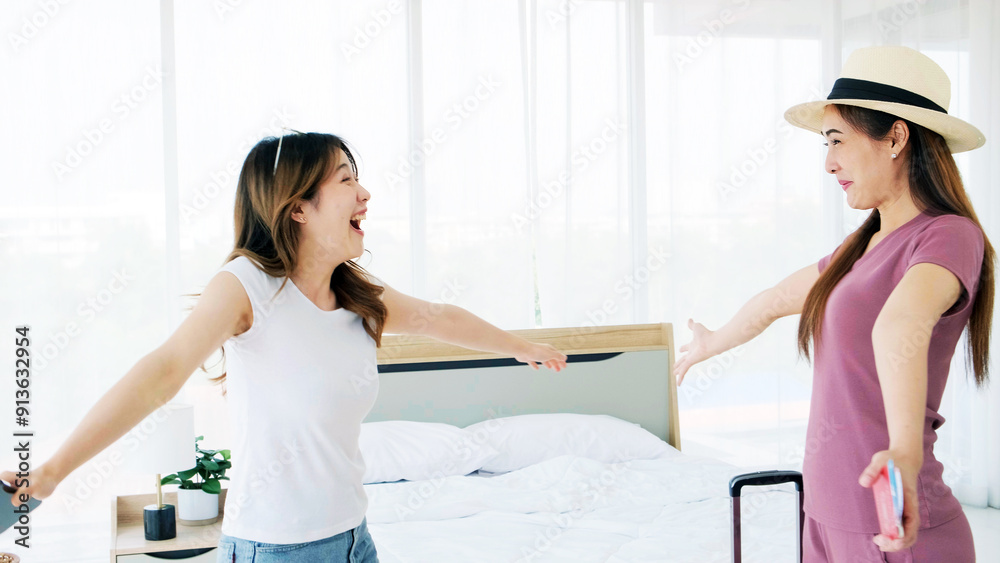 Fototapeta premium A happy young Asian woman hugging a woman carrying luggage from a trip is surprised that her friends have not seen each other for a long time. Expression of girl friendship.