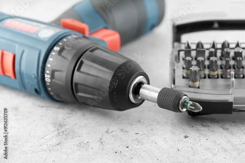 Professional cordless drill screwdriver and screwdriver bit set close-up. Quick-change universal holder with locking mechanism to ensure a secure hold and fast bits changes, emphasis on detail. photo