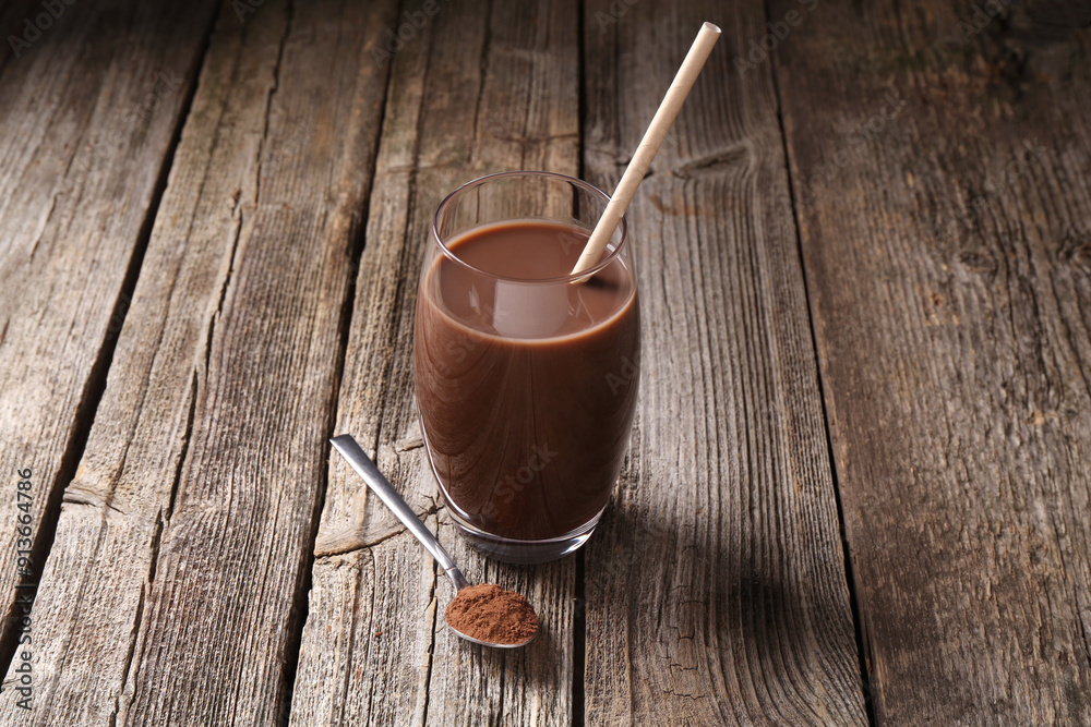 Delicious protein shake in glass and spoon with powder on wooden table Delicious protein shake in glass and spoon with powder on wooden table