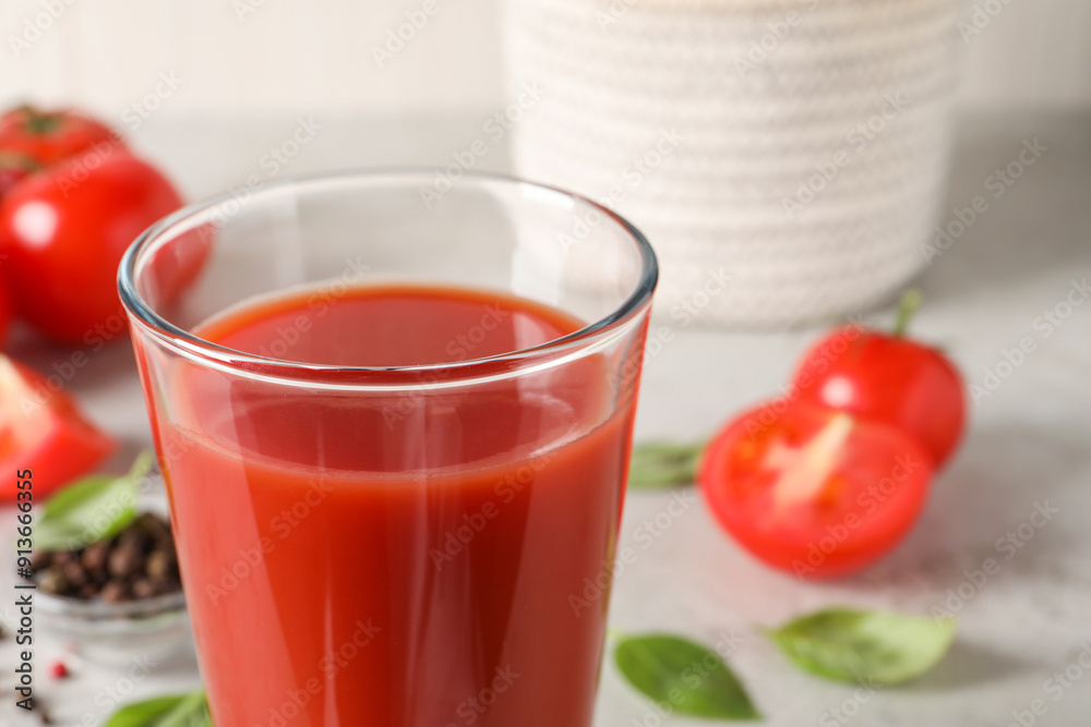 Tasty tomato juice in glass, basil leaves and fresh vegetables on table, closeup Tasty tomato juice in glass, basil leaves and fresh vegetables on table, closeup