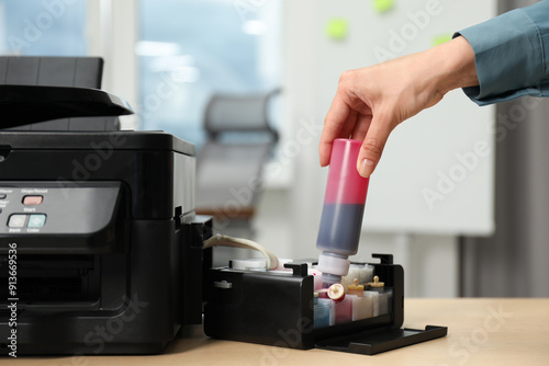 Woman refilling ink in modern printer at workplace indoors, closeup