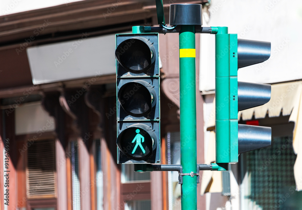 Traffic light displaying a green man walking sign, indicating it's safe for pedestrians to cross the street. Green crosswalk signal is lit up, indicating that pedestrians are allowed to cross street