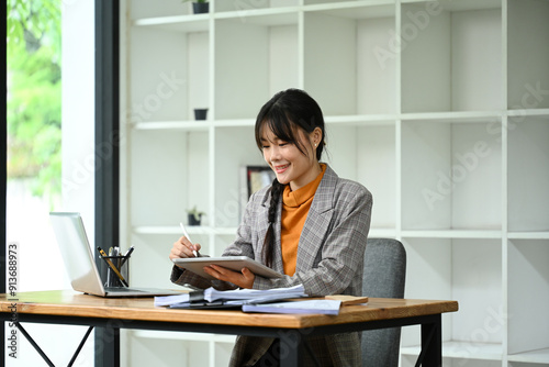 Asian female entrepreneur using her digital tablet and laptop in a modern office