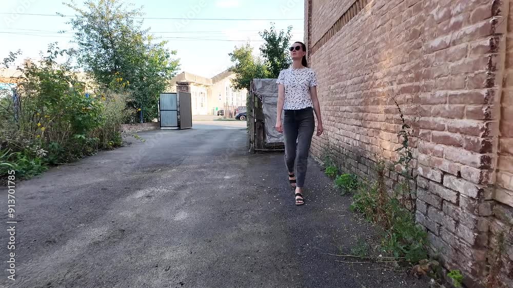 Woman walking in the city in summertime wearing jeans and t-shirt and sunglasses. Slow motion video Woman walking in the city in summertime wearing jeans and t-shirt and sunglasses. Slow motion video