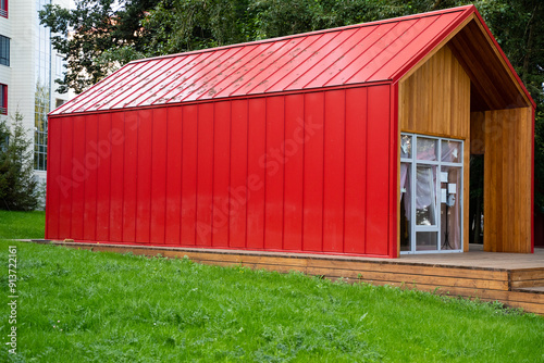 A striking red building that features a wellconstructed wooden frame along with a matching red roof is prominently located on top of a lush, vibrant green field that surrounds it photo