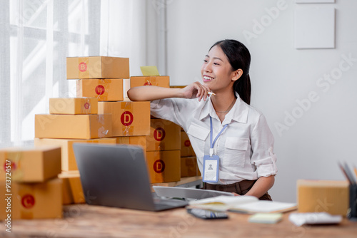 Young asian online seller businesswoman working shipping at home for online orders and thinking about her sme business future, good for online seller business sme concept.