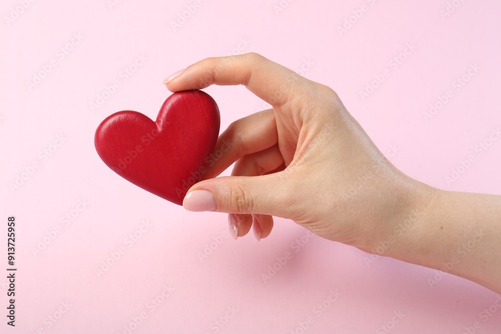Woman holding red heart on pink background, closeup