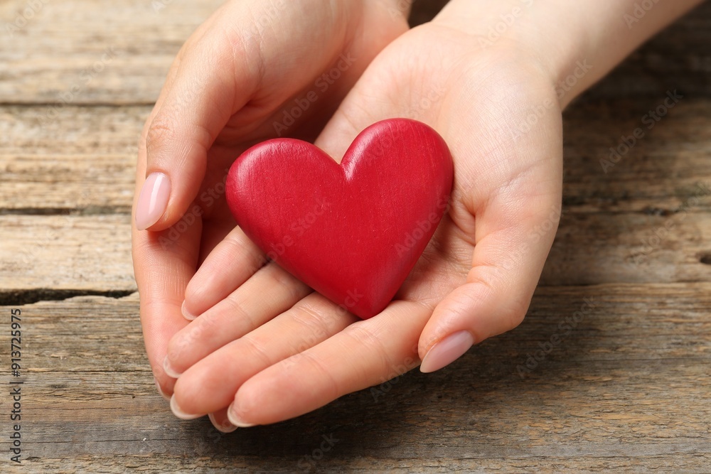 Woman with red decorative heart at wooden table, closeup Woman with red decorative heart at wooden table, closeup