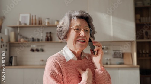 Wallpaper Mural Modern older Caucasian grandmother holding smartphone while having phone call. Pretty elderly woman friendly communicating from smartphone in cosy kitchen at home. Calling friends or relatives. Torontodigital.ca