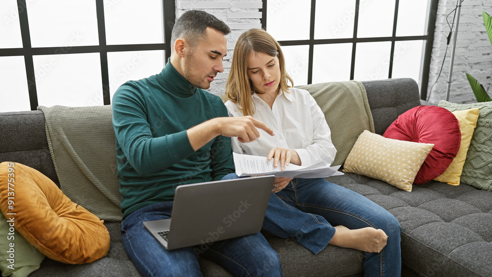 Fototapeta premium A couple reviews documents together in their modern living room, conveying a sense of partnership and home management.
