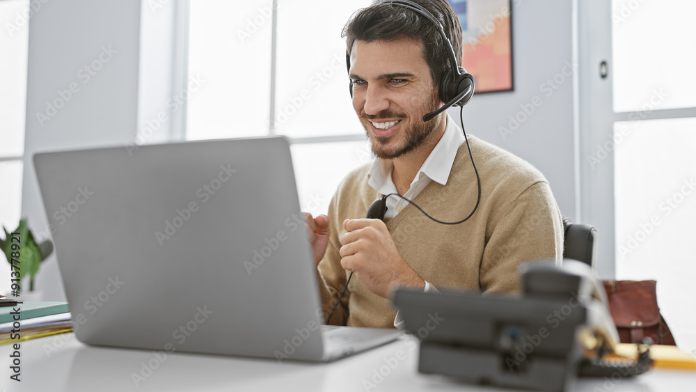 Handsome hispanic man with beard using laptop and headset in a bright office setting, exuding friendly professionalism. Handsome hispanic man with beard using laptop and headset in a bright office setting, exuding friendly professionalism.