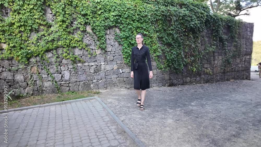 Woman walking in the city wearing elegant black dress Woman walking in the city wearing elegant black dress