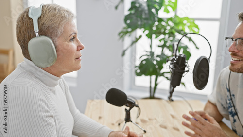 Quadro em tela A woman and a man converse indoors during a podcast recording session surrounded by equipment