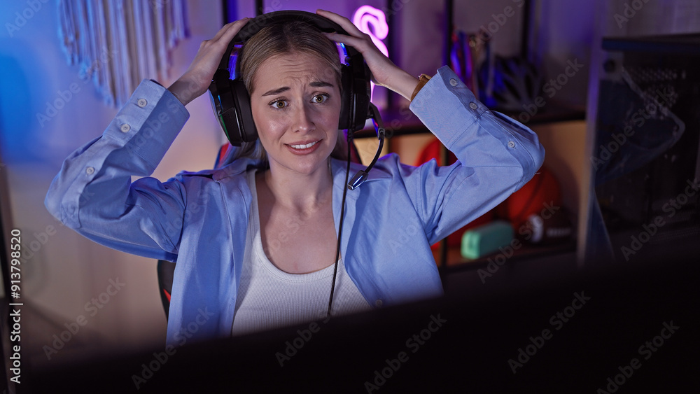 A confused young woman adjusts her headset in a dark gaming room at night. A confused young woman adjusts her headset in a dark gaming room at night.