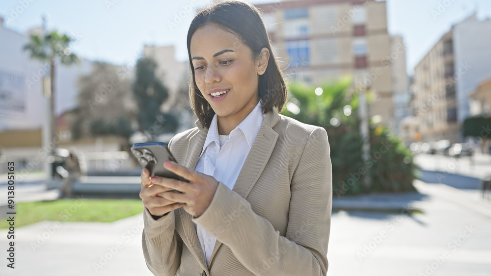 A stylish young woman texting on her smartphone while standing on a sunny urban street. A stylish young woman texting on her smartphone while standing on a sunny urban street.