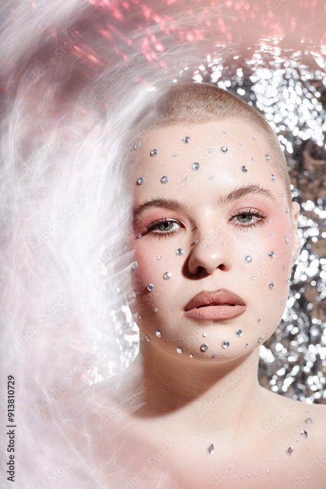 Vertical closeup portrait of young woman with creative makeup and gem stickers on face looking at camera on metallic background Vertical closeup portrait of young woman with creative makeup and gem stickers on face looking at camera on metallic background
