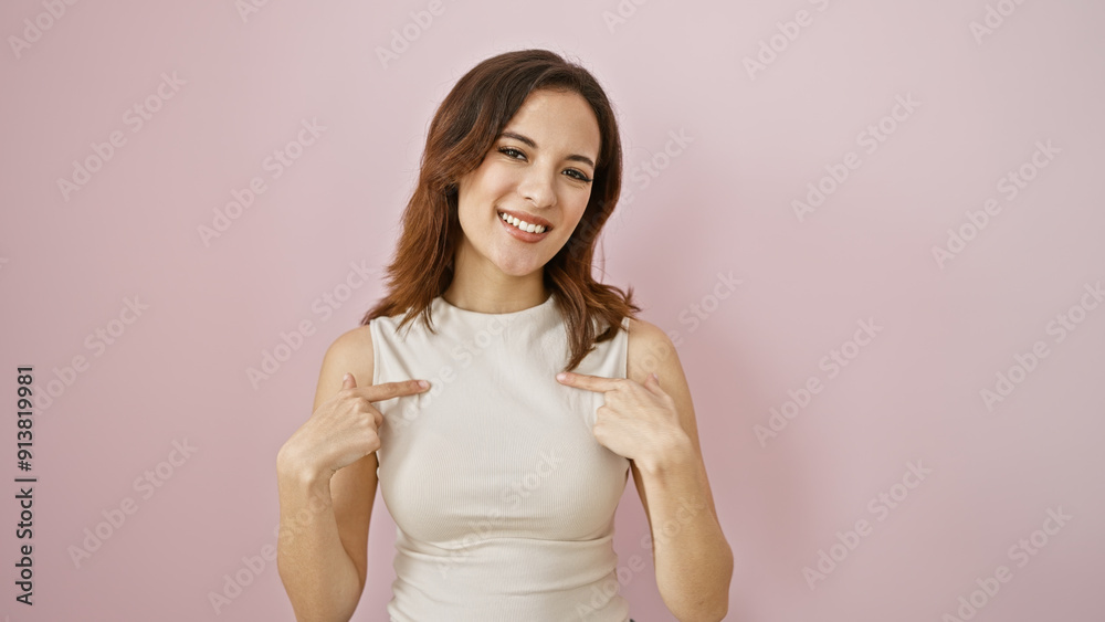 Young hispanic woman with a confident smile, pointing to herself against a pink background. Young hispanic woman with a confident smile, pointing to herself against a pink background.