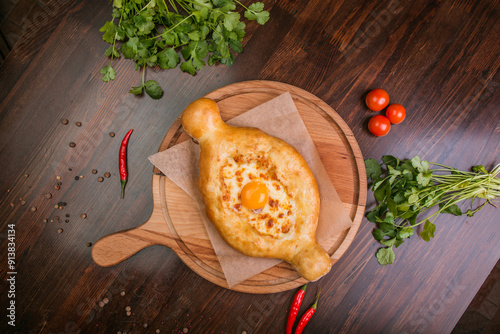 khachapuri with sulguni cheese, herbs and egg on a wooden surface. Georgian pie. Georgian pizza
 photo