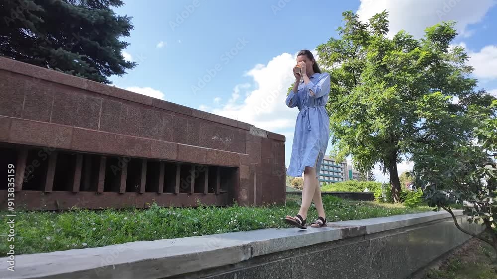 Woman walking in the city park in summertime wearing blue dress Woman walking in the city park in summertime wearing blue dress