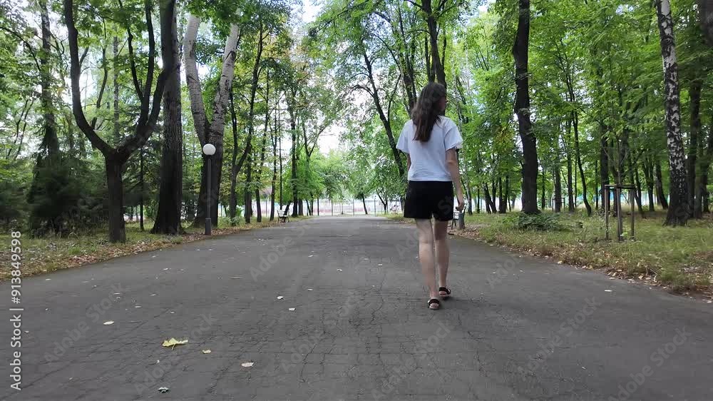 Woman walking in the city park on a sunny summer day with a tote bag Woman walking in the city park on a sunny summer day with a tote bag