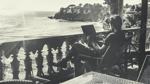 A happy man, on a laptop with a nice view on cliffs and sea, on a balcony
