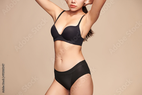 Confident beautiful young asian woman posing in black lingerie on beige background, Perfect body,