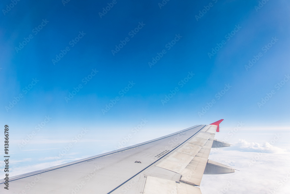 Fototapeta premium View from the airplane window at a beautiful cloudy sky and the airplane wing