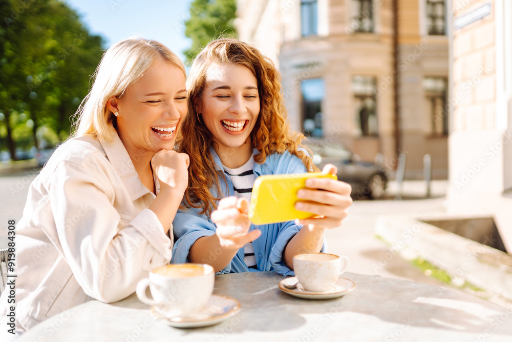 Happy women drinking coffee and using mobile phone while sitting at the summer street cafe. Fashion, beauty, blogging, tourism. Happy women drinking coffee and using mobile phone while sitting at the summer street cafe. Fashion, beauty, blogging, tourism.