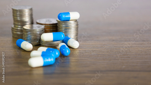 Blue and white capsules on and around a stack of coins for disign health insurance, medical expenses and medicine, finance, saving money, business . financial and medical healthcare concepts.