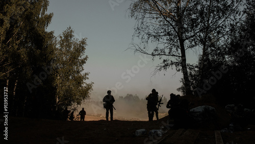 Φωτογραφία Silhouettes of a group of infantrymen with machine guns in the shade of trees in