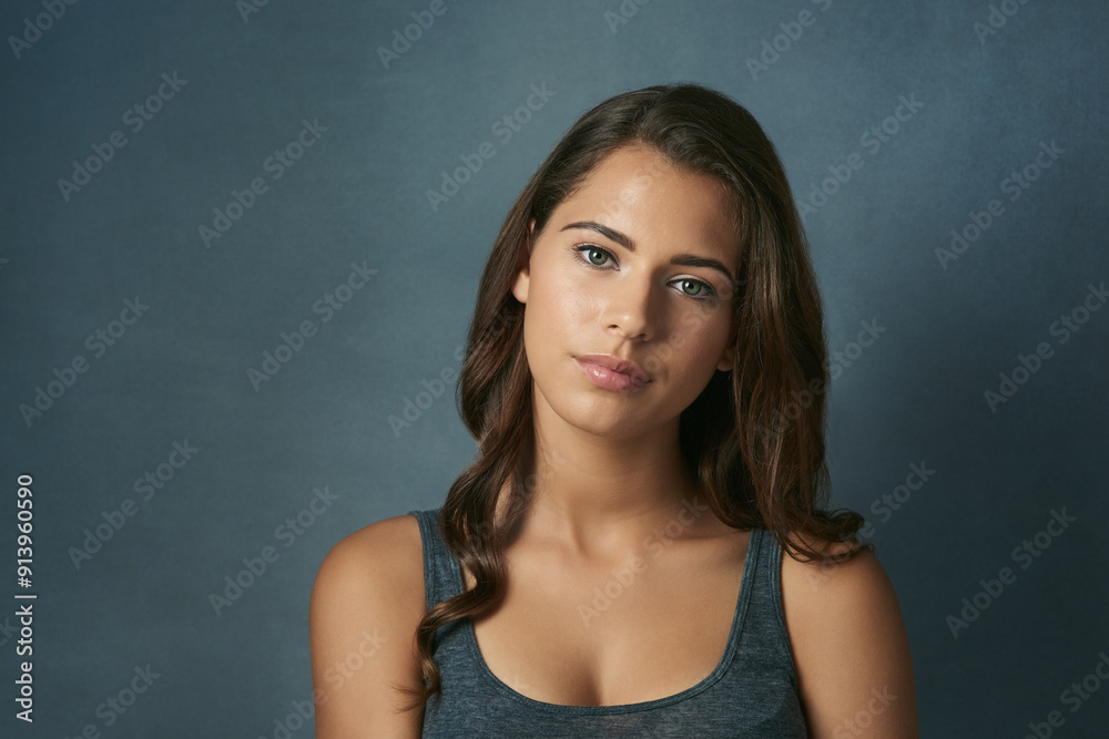 Hair care, makeup and portrait of woman in studio with volume, collagen and salon treatment. Cosmetic, serious and female person with shiny, long and curly hairstyle by blue background with space Hair care, makeup and portrait of woman in studio with volume, collagen and salon treatment. Cosmetic, serious and female person with shiny, long and curly hairstyle by blue background with space