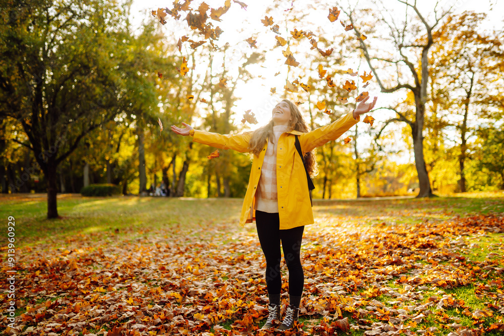 Smiling young woman with hands up throws up the bunch of autumn leaves in the forest. Beautiful place. The concept of relaxation, fun, solitude with nature. Smiling young woman with hands up throws up the bunch of autumn leaves in the forest. Beautiful place. The concept of relaxation, fun, solitude with nature.