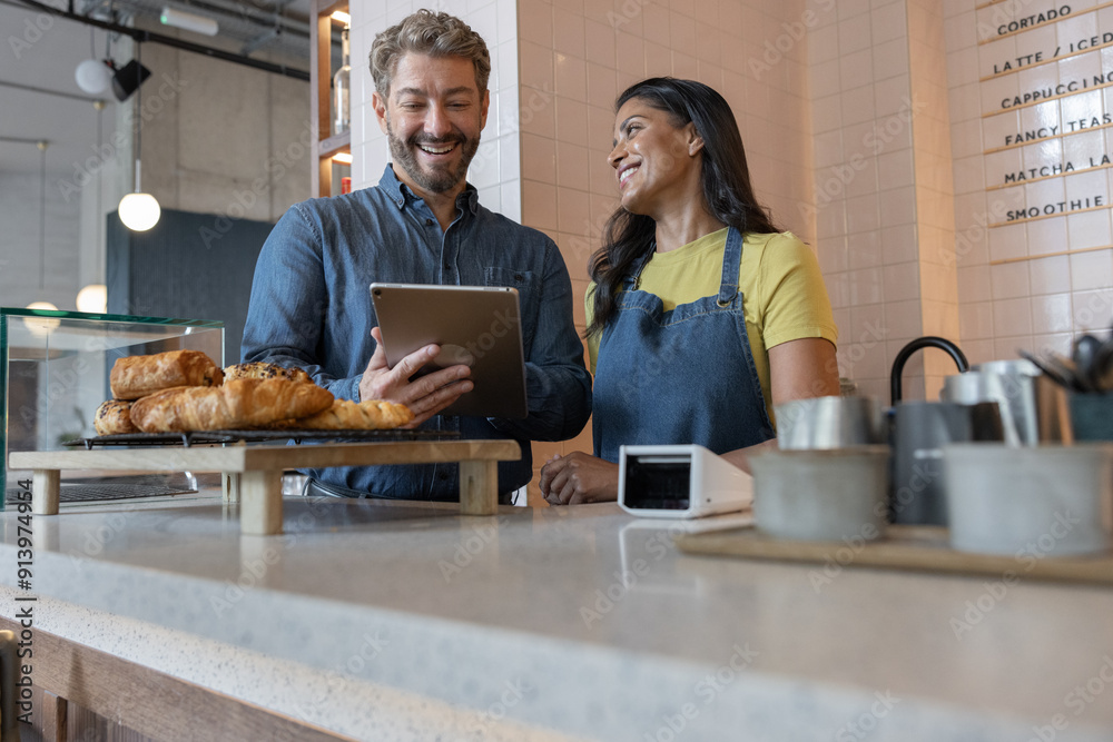 Happy cafe business owners looking at finances on digital tablet Happy cafe business owners looking at finances on digital tablet