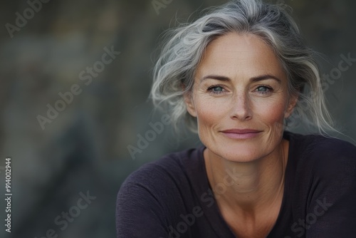A graceful older woman with fine grey hair, sits in a contemplative pose, beautifully captured in soft lighting, showcasing her elegant features and serene demeanor.