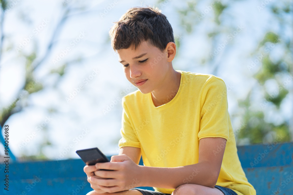 Smiling kid boy sitting with cell phone in empty football stadium and communicating online Smiling kid boy sitting with cell phone in empty football stadium and communicating online