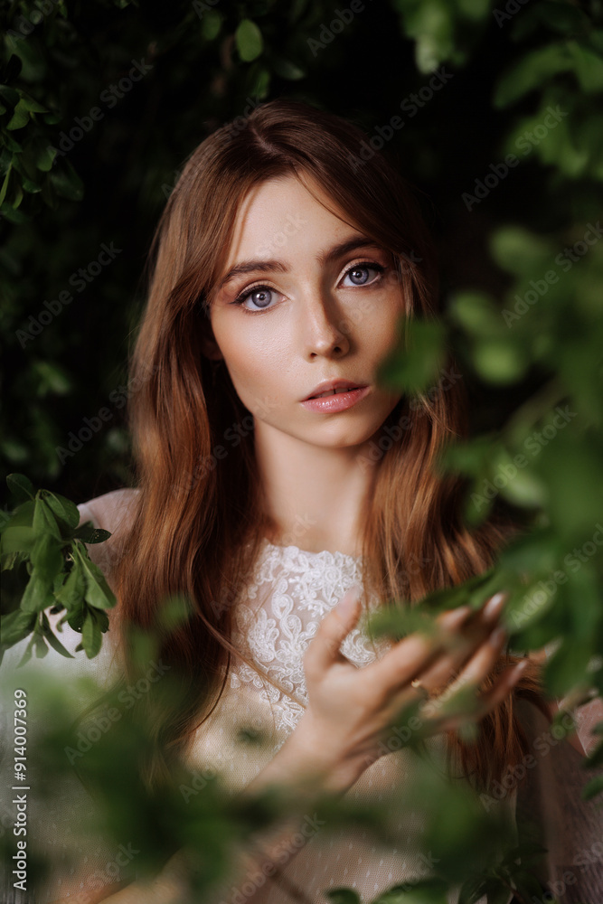 A young woman in a long dress made of delicate and light transparent fabric poses in an evening park. A concept of a show of wedding and summer dresses or a model's portfolio. A young woman in a long dress made of delicate and light transparent fabric poses in an evening park. A concept of a show of wedding and summer dresses or a model's portfolio.