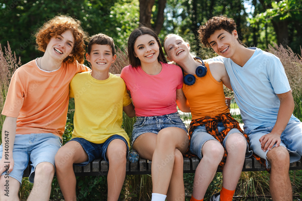 Happy teenagers hugging sitting on the bench in the park Happy teenagers hugging sitting on the bench in the park